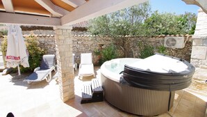An outdoor hot tub area with stone walls, lounge chairs, and a pergola. - Elegant Holiday House in Village Kavran  (Kavran)