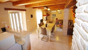 A spacious kitchen with a dining area, wooden ceiling beams, and a brick wall. - Elegant Holiday House in Village Kavran  (Kavran)