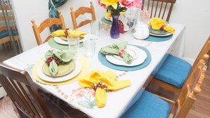 A dining table set with plates, glasses, and a vase of flowers.