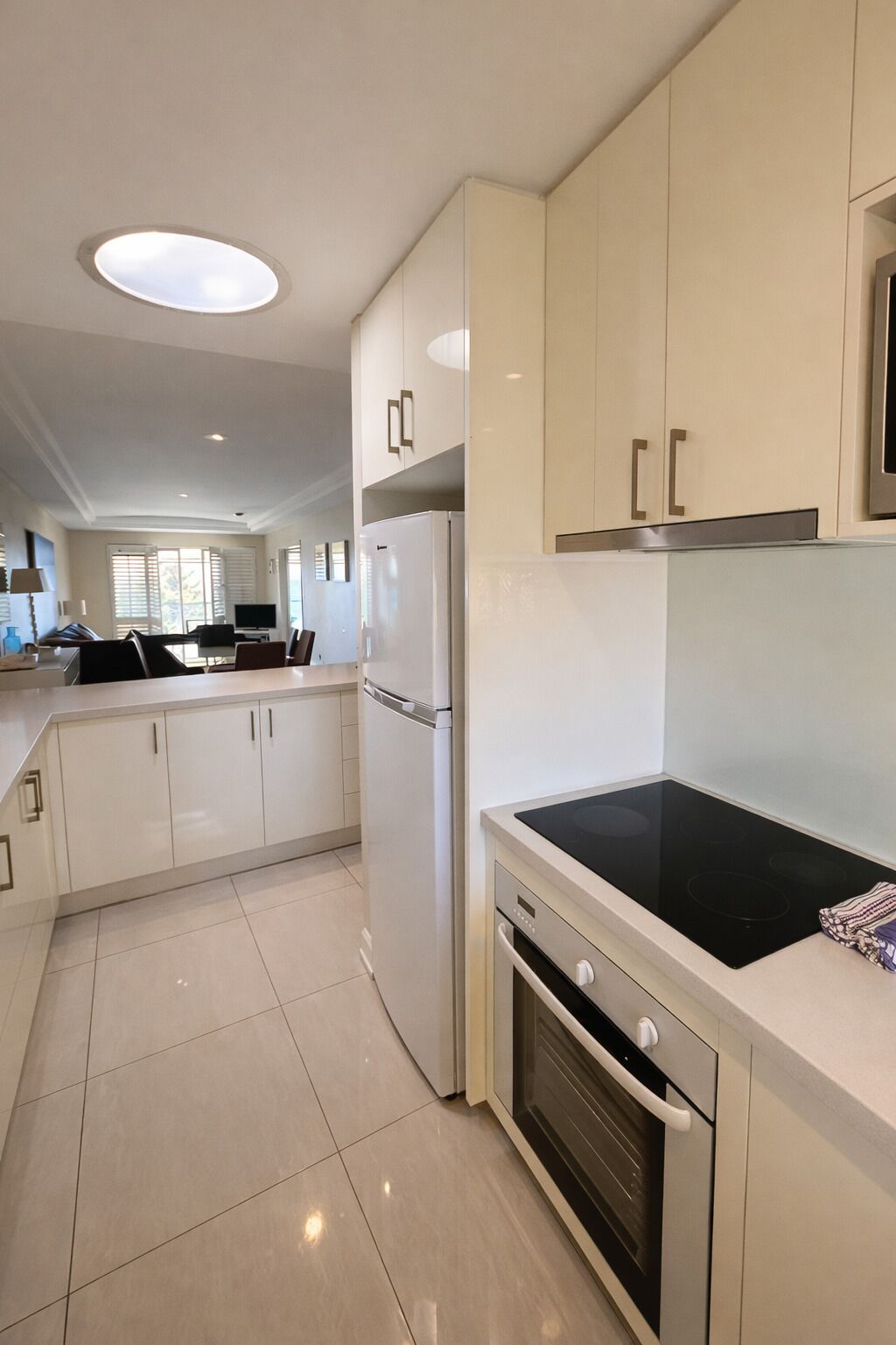 A modern kitchen with white cabinets, a built-in oven, and a black stovetop.