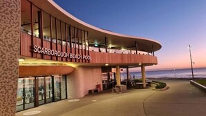 Un bâtiment moderne à la façade incurvée, sur lequel on peut lire l’inscription « Scarborough Beach Pool ».