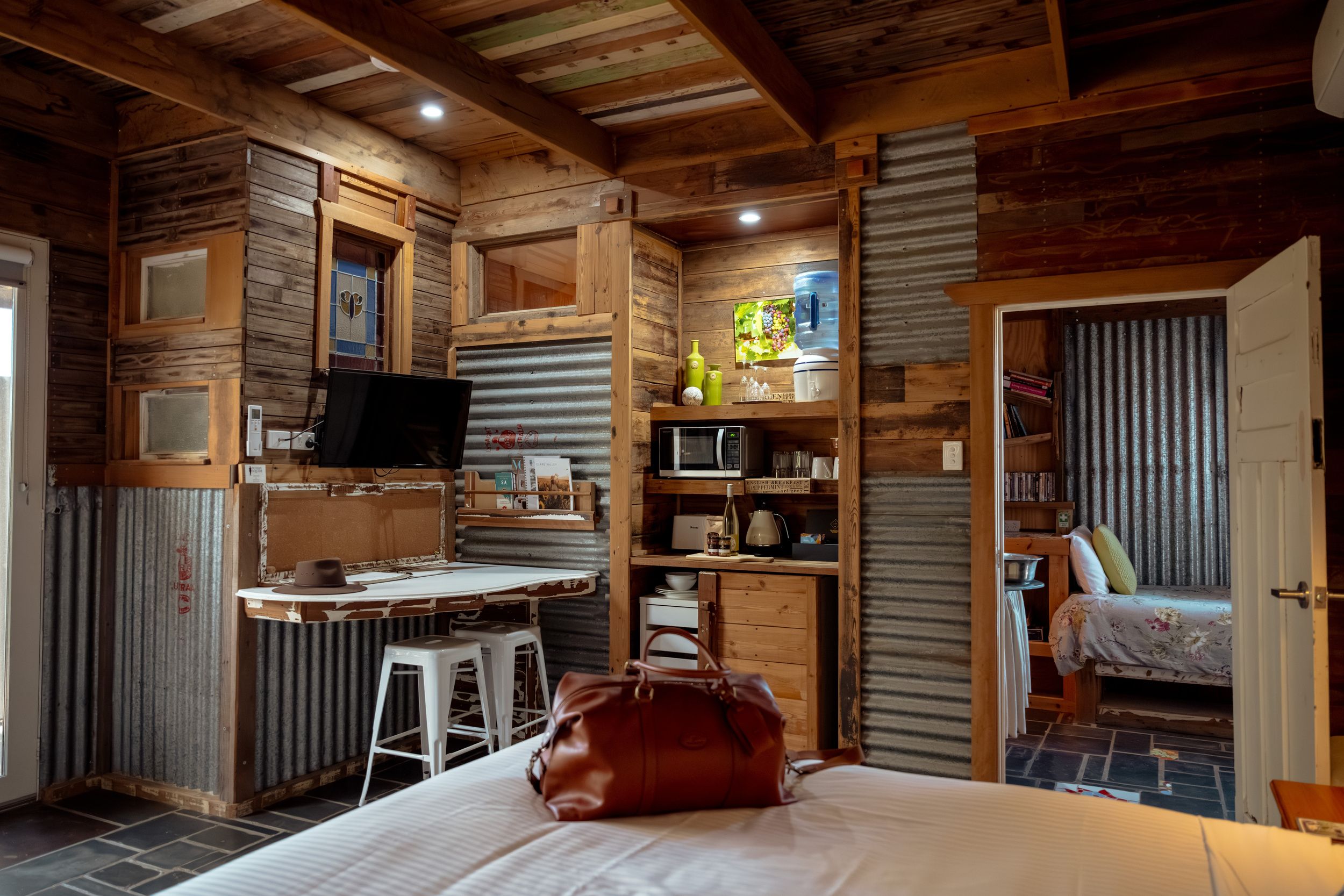 Um quarto acolhedor com uma cama, uma escrivaninha, uma cadeira, uma televisão e uma estante de livros.