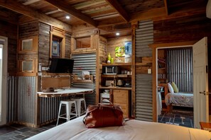 A cozy room with a bed, a desk, a chair, a television, and a bookshelf.