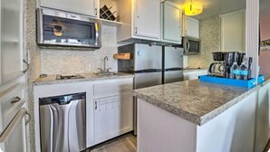 A modern kitchen with white cabinets, stainless steel appliances, a microwave, and a coffee maker. - OF Condo Gone2TheBeach @ Symphony Beach Club (Ormond Beach)