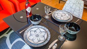 Une table à manger dressée avec des assiettes, des bols, des couverts et une bouteille de vin.