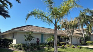 A residential house with a tiled roof, a well-maintained lawn, and various plants. - Waterfront Vacation home, Private Pool, Lanai, Dock, Walk to Beach (Marco Island)