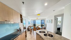 Una cocina moderna con una isla grande, un comedor con vistas y un balcón con vista al océano.