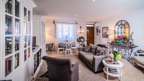 Un salon comprenant un canapé, un fauteuil, une table à manger et un miroir décoratif.
