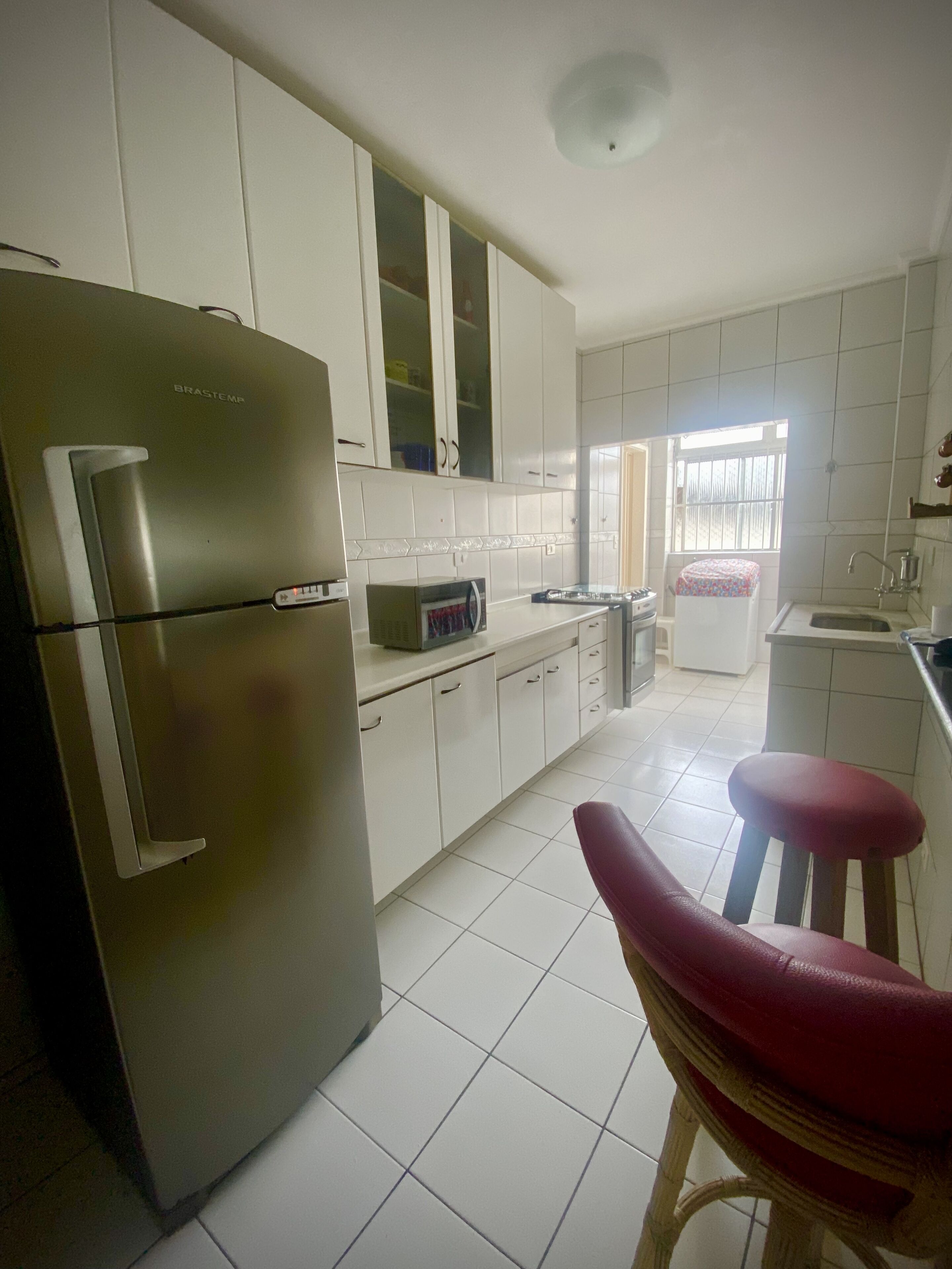 A kitchen with white cabinets, a stainless steel refrigerator, a microwave, and a sink.