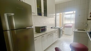 Et køkken med hvide skabe, et rustfrit stål køleskab, en mikrobølgeovn og en vask.