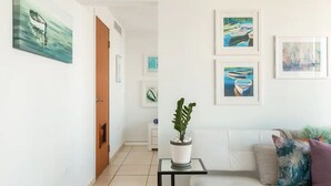 A modern living room with a sofa, a coffee table, and a potted plant. There are framed artworks on the wall. - Ocean View  Studio  Apt In the heart of Condado 21 floor with parking  (San Juan)