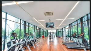 Une salle de sport équipée de machines de cardio, d’appareils de musculation et d’un écran de télévision.