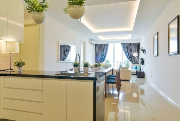Une cuisine moderne dotée d’un îlot central, de meubles blancs et de plantes suspendues.