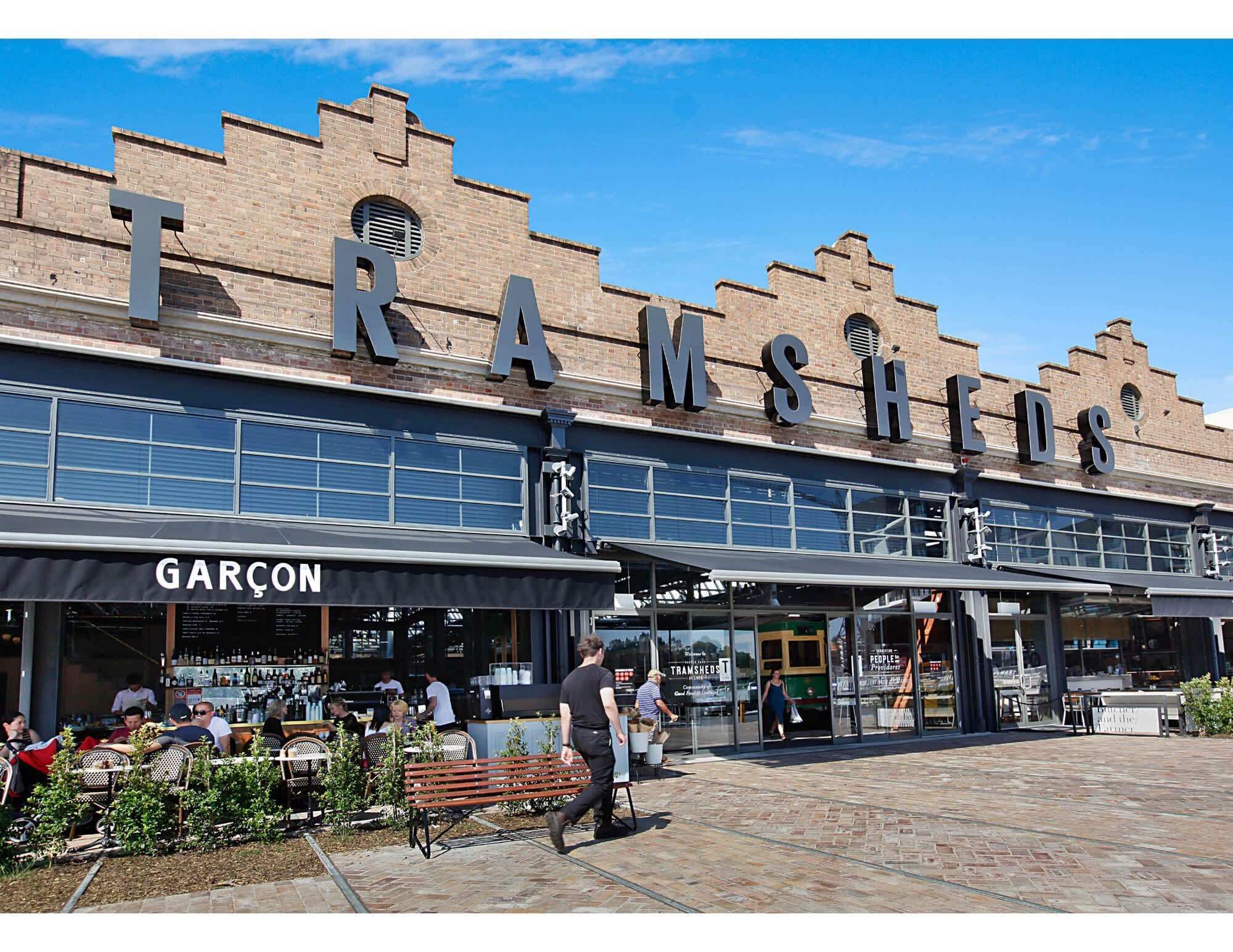 Ein Gebäude mit der Aufschrift 'TRAMSHED'S' und einem Restaurant 'GARÇON'.
