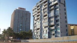 Un immeuble à plusieurs étages doté de balcons, qui pourrait être un hôtel ou un ensemble d’appartements.