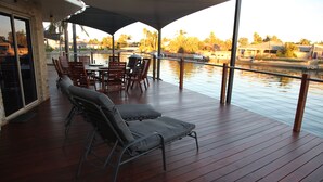 Terraza cubierta al aire libre con una mesa y sillas, con vista a una masa de agua.