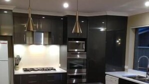 Una cocina moderna con armarios oscuros, electrodomésticos de acero inoxidable e iluminación colgante.