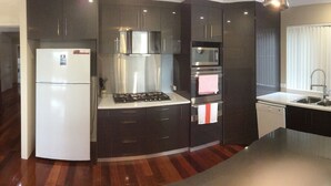 Una cocina moderna con armarios oscuros, un refrigerador blanco y un comedor con mesa y sillas de madera.