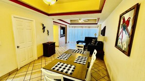 A dining area with a checkered tablecloth, a ceiling fan, and a painting of parrots. - Beautiful 2 Bedroom Condo on the Sea of Cortez at Las Palmas Resort D-404 (Puerto Peñasco)