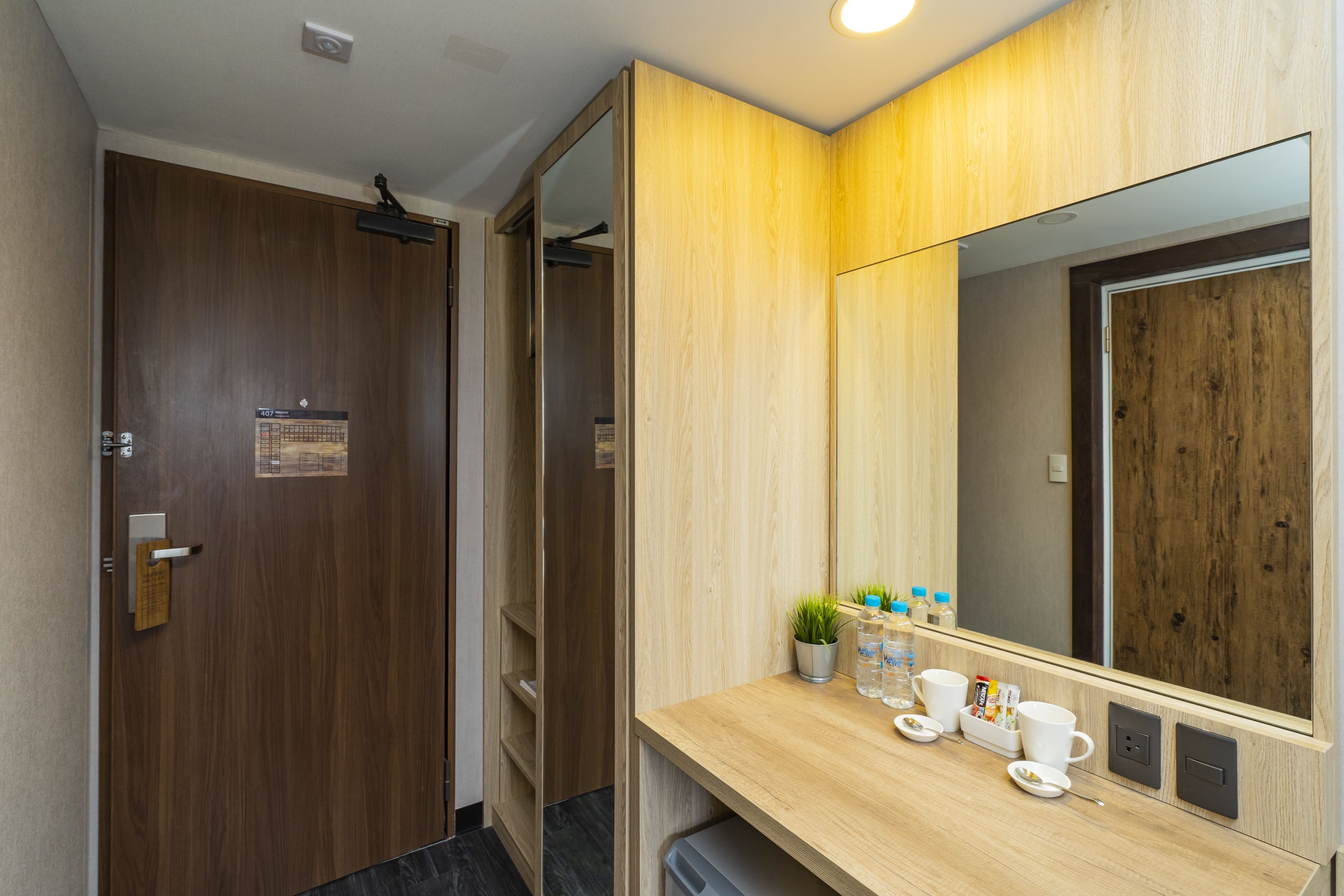 Un baño moderno con tocador de madera, un espejo grande y una pequeña planta en maceta.