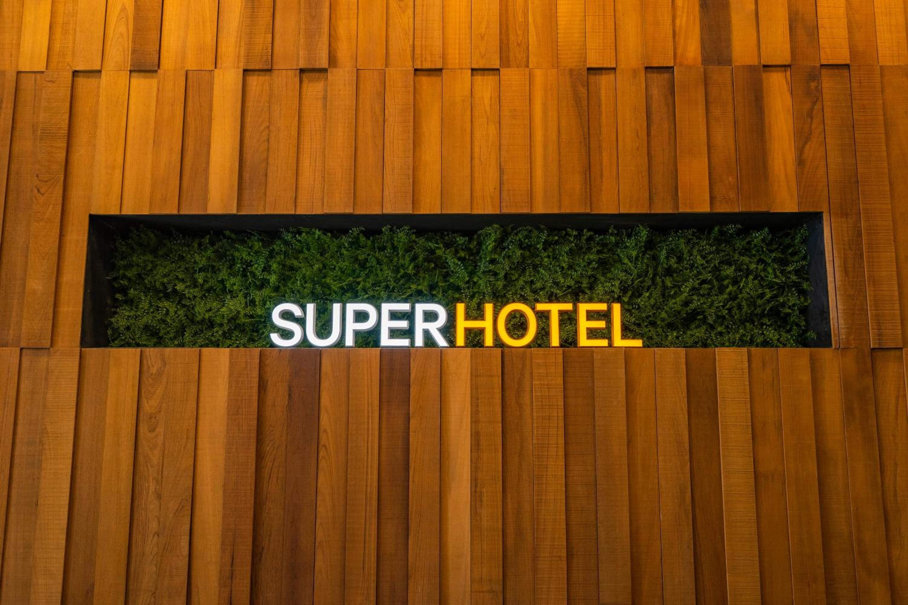 A wooden wall with a sign that reads "SUPERHOTEL".