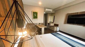 A hotel room with a bed, a desk, a chair, a hanging light fixture, and a television on the wall. - Super Hotel Thilawa (Yangon)