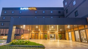 A modern hotel entrance with a "SuperHotel" sign, a covered outdoor area, and a brick facade. - Super Hotel Thilawa (Yangon)