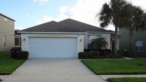 A single-story house with a white garage door, a driveway, and a well-maintained lawn.