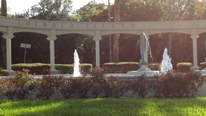 A sign reading "Emerald Island" with a fountain and well-maintained garden in the foreground.