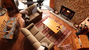 A cozy living room with a stone fireplace, two sofas, a coffee table, and a dining area with chairs and a table.