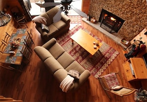 A cozy living room with a stone fireplace, two sofas, a coffee table, and a dining area with chairs and a table.