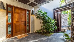 Una puerta de madera con un panel de vidrio, una pared de piedra y un área de entrada con baldosas y un felpudo.