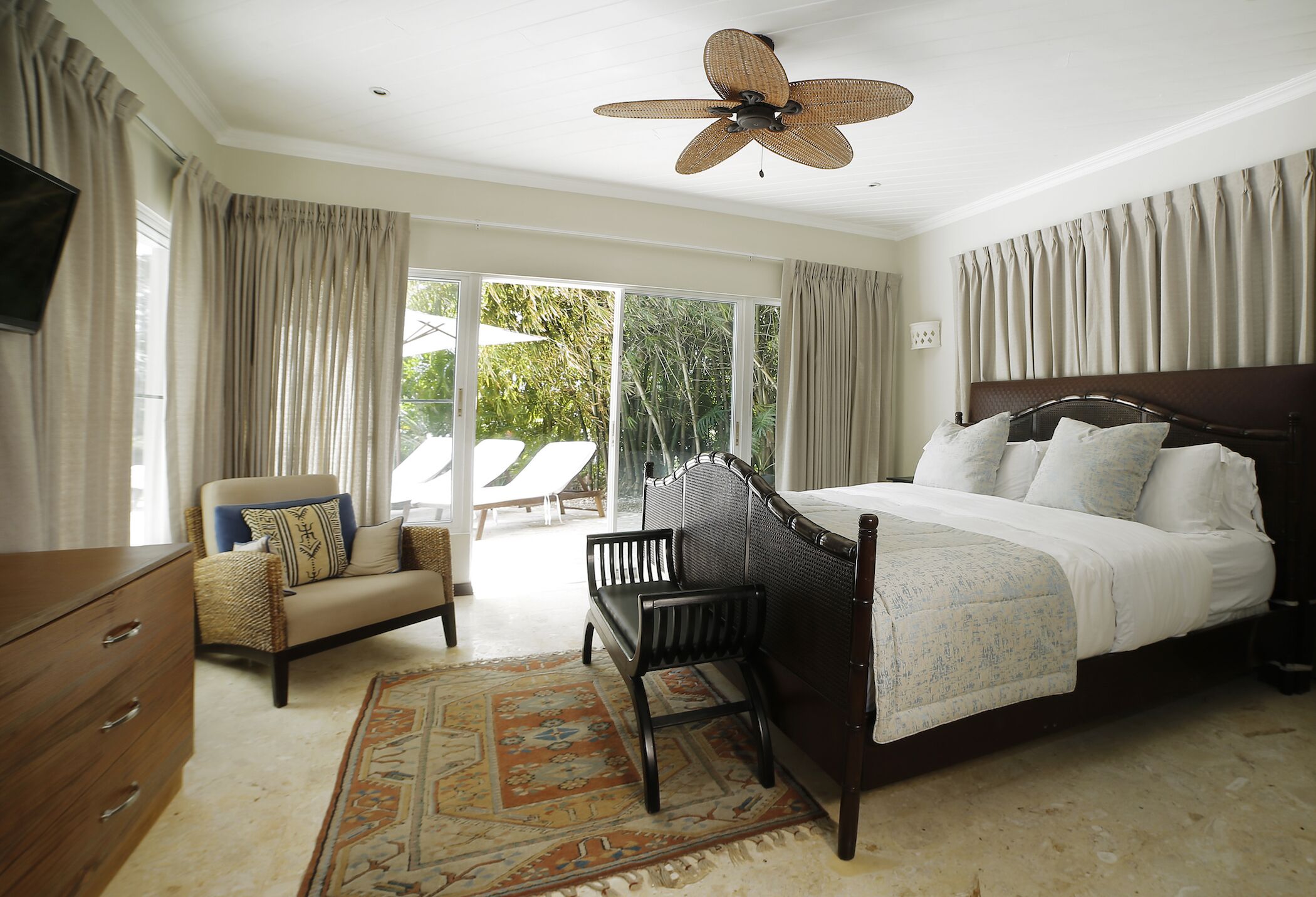 A bedroom with a bed, a chair, a dresser, and a ceiling fan.