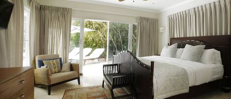 A bedroom with a bed, a chair, a dresser, and a ceiling fan.
