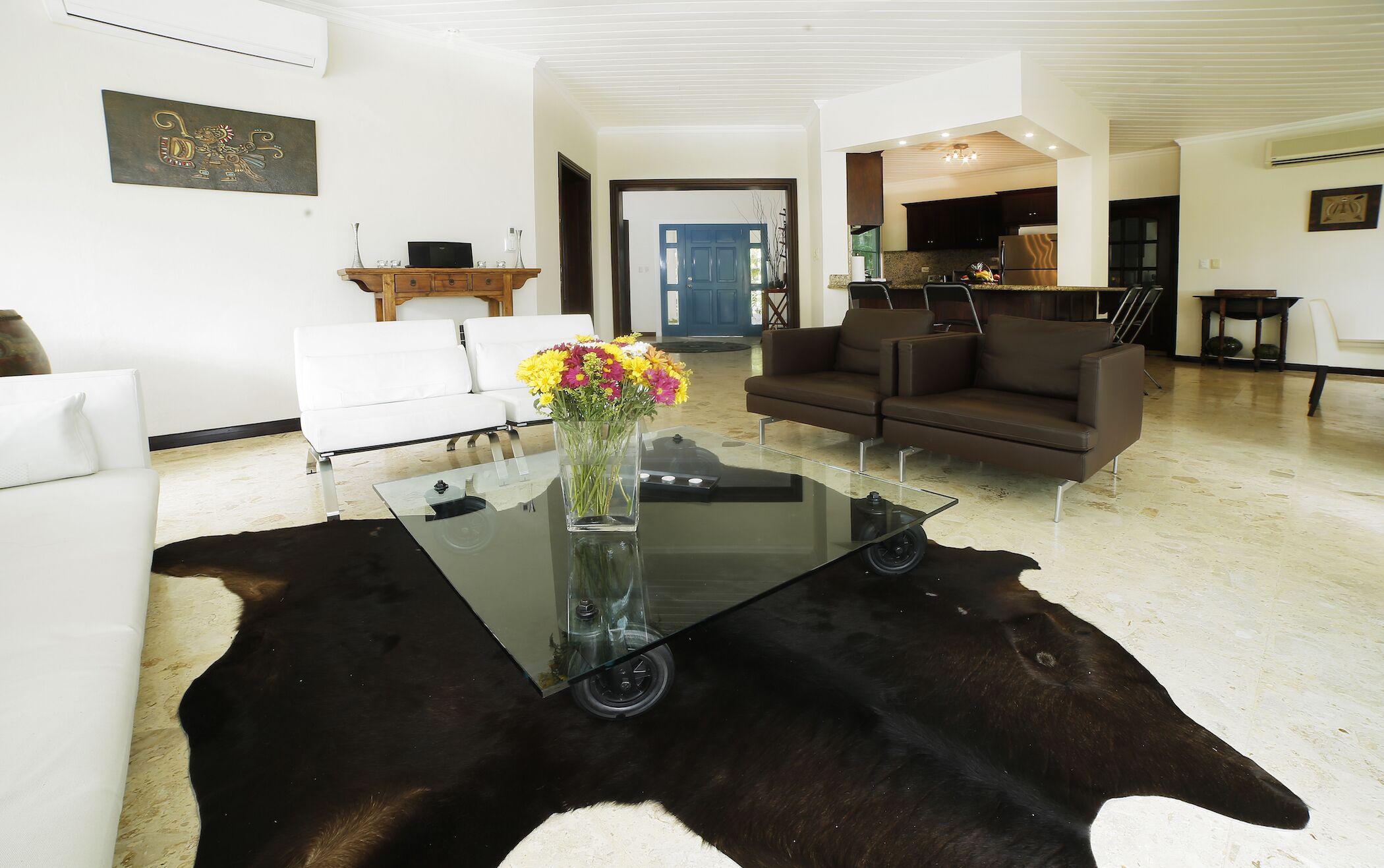 Un salon moderne avec une table basse en verre, des canapés en cuir et un tapis en peau de vache.