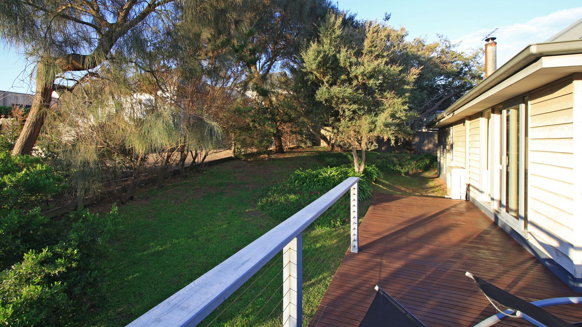 Un pontile in legno con ringhiera, circondato da un prato e alberi.