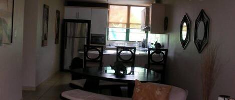 Un espacio habitable compacto con comedor, kitchenette y una pequeña zona de estar.