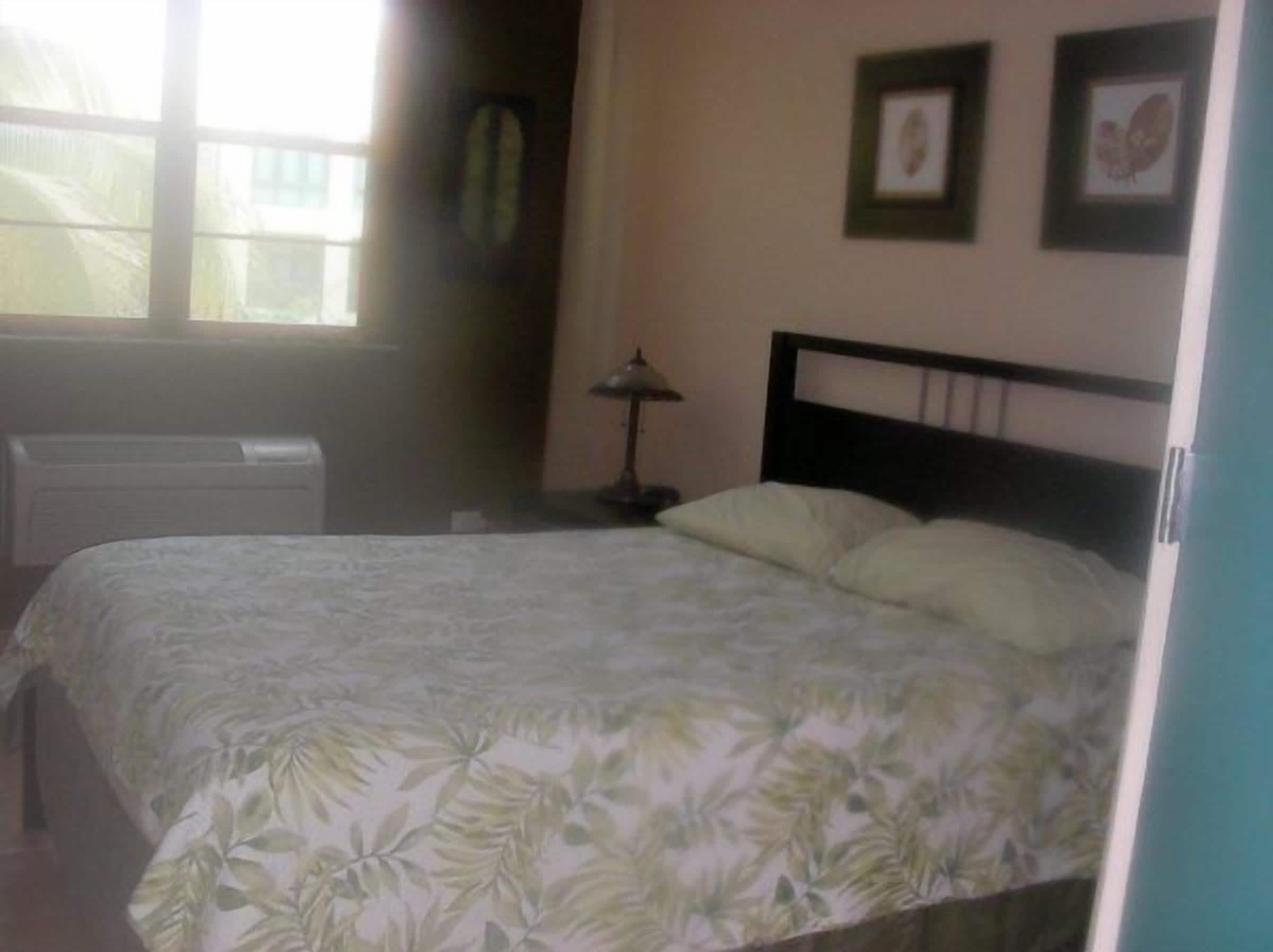 Un dormitorio con cama, radiador, lámpara y cuadros en la pared.