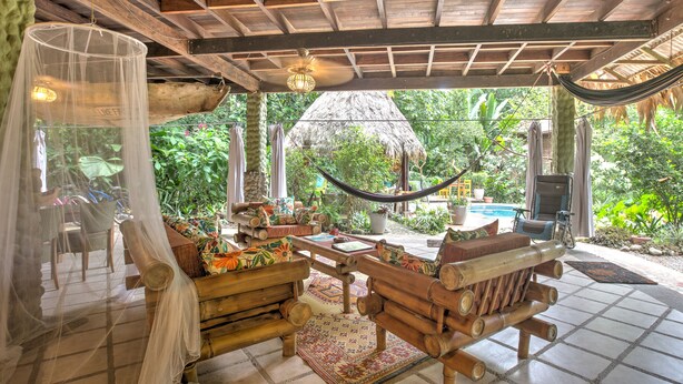 A wooden outdoor seating area with a hammock, a thatched roof, and lush greenery. - Book now!!  Free EGGS!! Also pool, 300m to beach and great gardens! (Playa Chiquita)