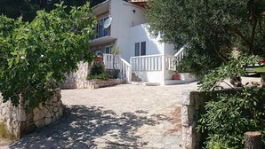 A stone pathway leading to a white building with a balcony and potted plants. - Apartments Arboreum A2 (5+2) (Ivan Dolac)