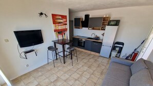 A compact living space with a kitchenette, a dining area with a table and chairs, a sofa, and a television mounted on the wall. - Apartments Arboreum A2 (5+2) (Ivan Dolac)