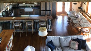 A spacious loft with a high ceiling, exposed wooden beams, a kitchen area, dining space, and a cozy seating area with a sofa and chairs. - Hope House on Rhode Island's South Shore sits on 6 private acres (Little Compton)