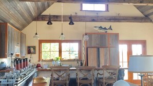 A rustic kitchen with wooden beams, a large ship model, and a dining area with wooden chairs. - Hope House on Rhode Island's South Shore sits on 6 private acres (Little Compton)