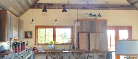 A rustic kitchen with wooden beams, a large ship model, and a dining area with wooden chairs.