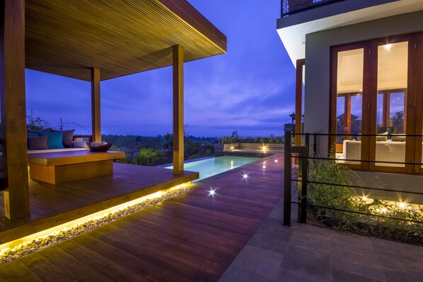 A modern outdoor deck with a pool, wooden flooring, and ambient lighting. - Ocean View Villa Bali (Ungasan)