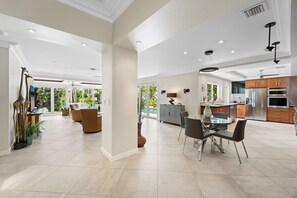 Amplia sala de estar con mesa de comedor, cocina moderna y ventanas grandes que ofrecen vistas al exterior.