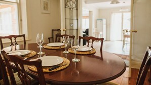 A dining table set with plates, cutlery, and wine glasses, surrounded by wooden chairs. - Cooke Cottage- Right on the Riesling Trail (Clare)