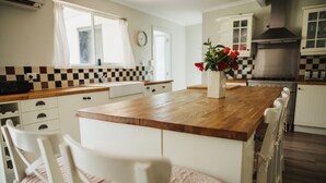 A kitchen with a wooden island, white chairs, and a vase with flowers. - Cooke Cottage- Right on the Riesling Trail (Clare)