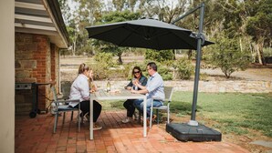 A patio with a table and chairs, a brick wall, and a stone wall in the background. - Cooke Cottage- Right on the Riesling Trail (Clare)