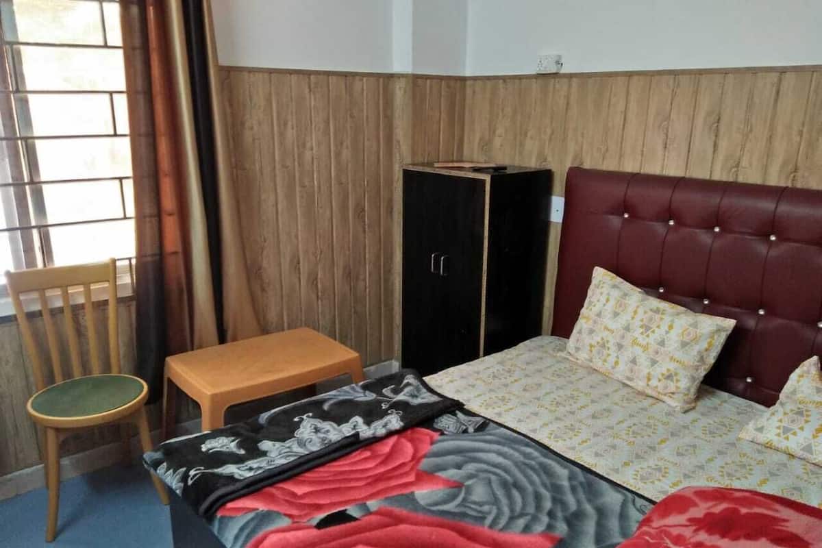 A bedroom with a bed, a wooden chair, a small table, and a wardrobe.